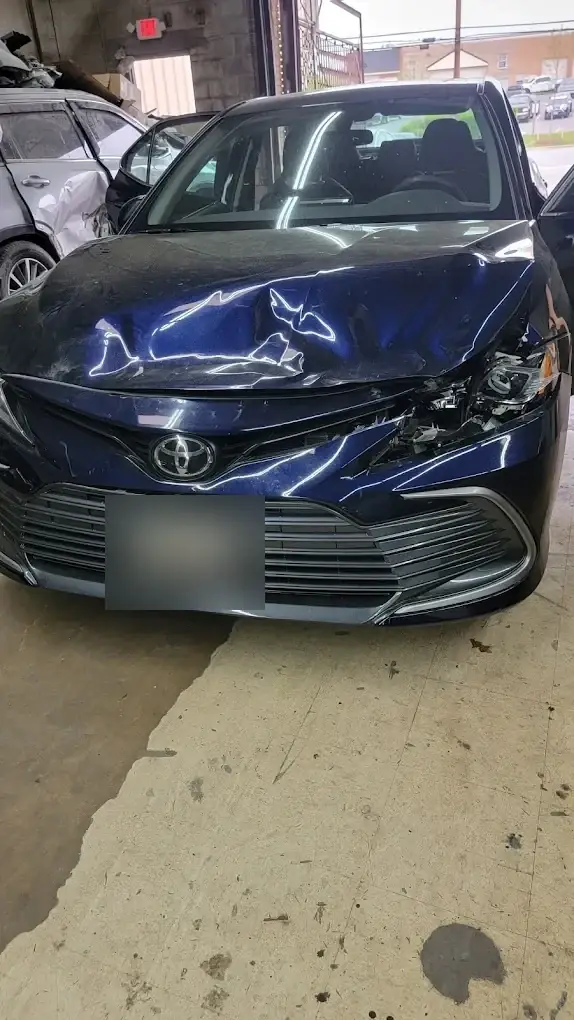 Toyota Camry with front-end collision damage in the Kenny Auto Body shop